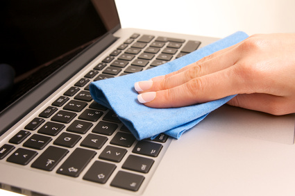 detalle de la mano de una mujer limpiando el teclado de un ordenador con una bayeta